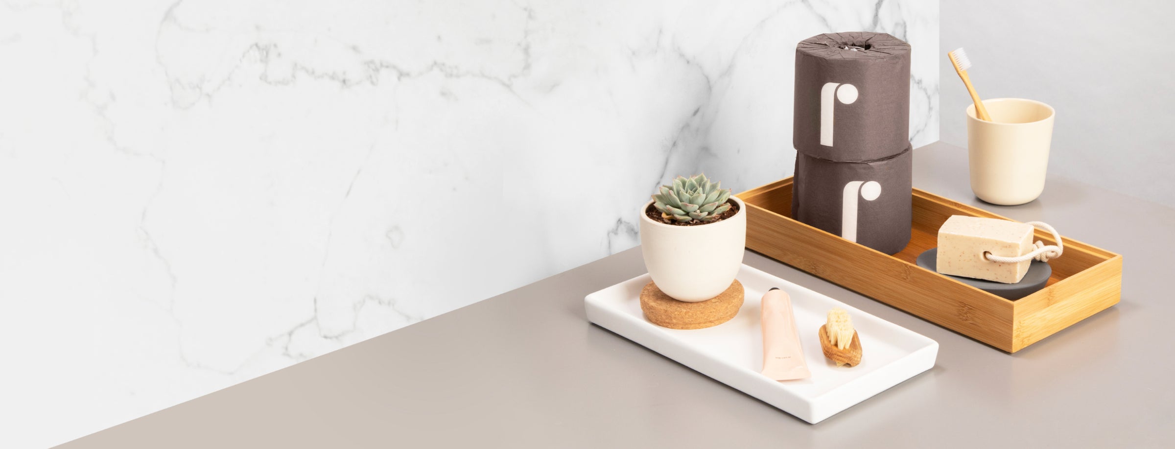 A stack of two rolls of Reel toilet paper on a bathroom counter.
